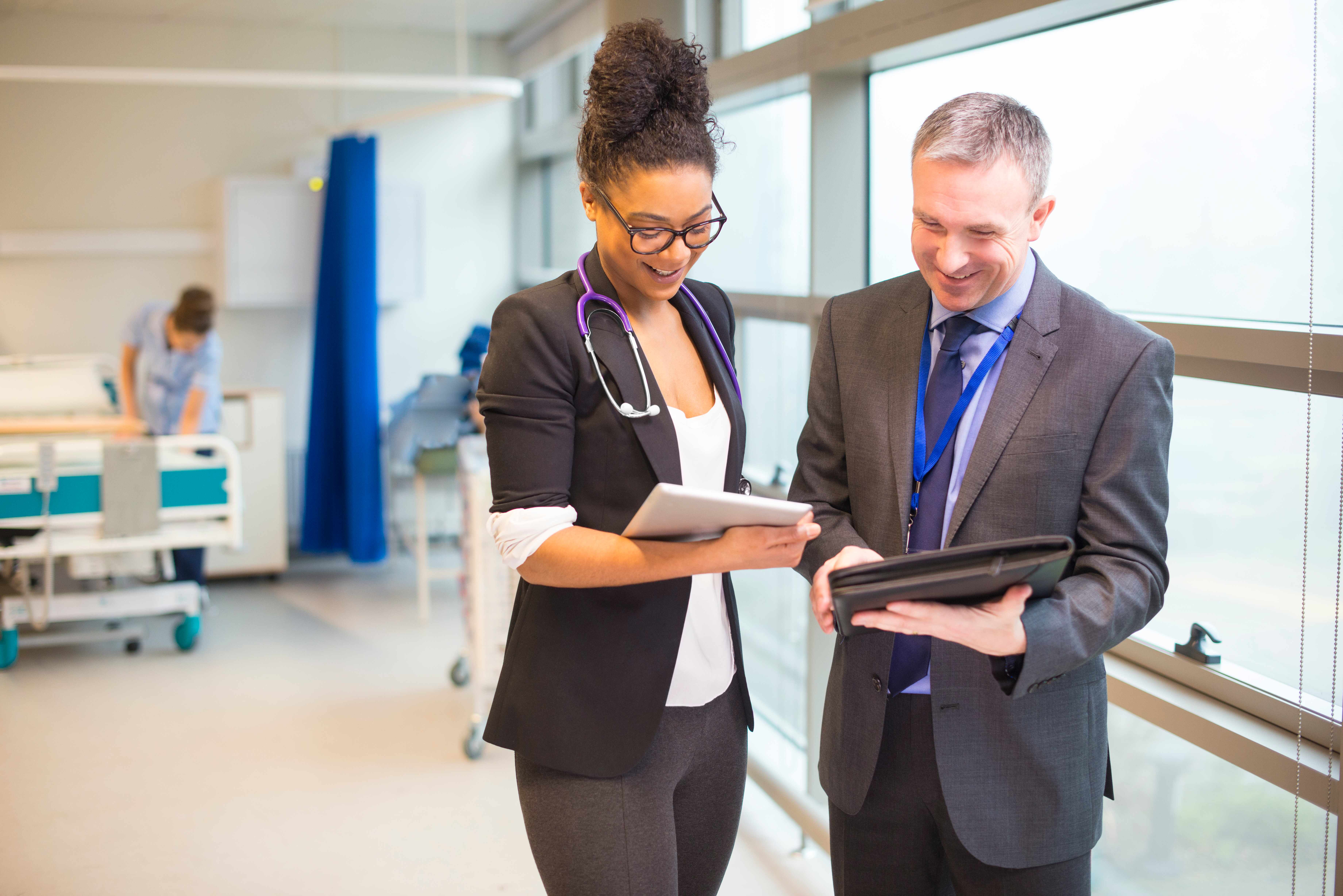 two doctors reviewing notes and smiling in a hospital room