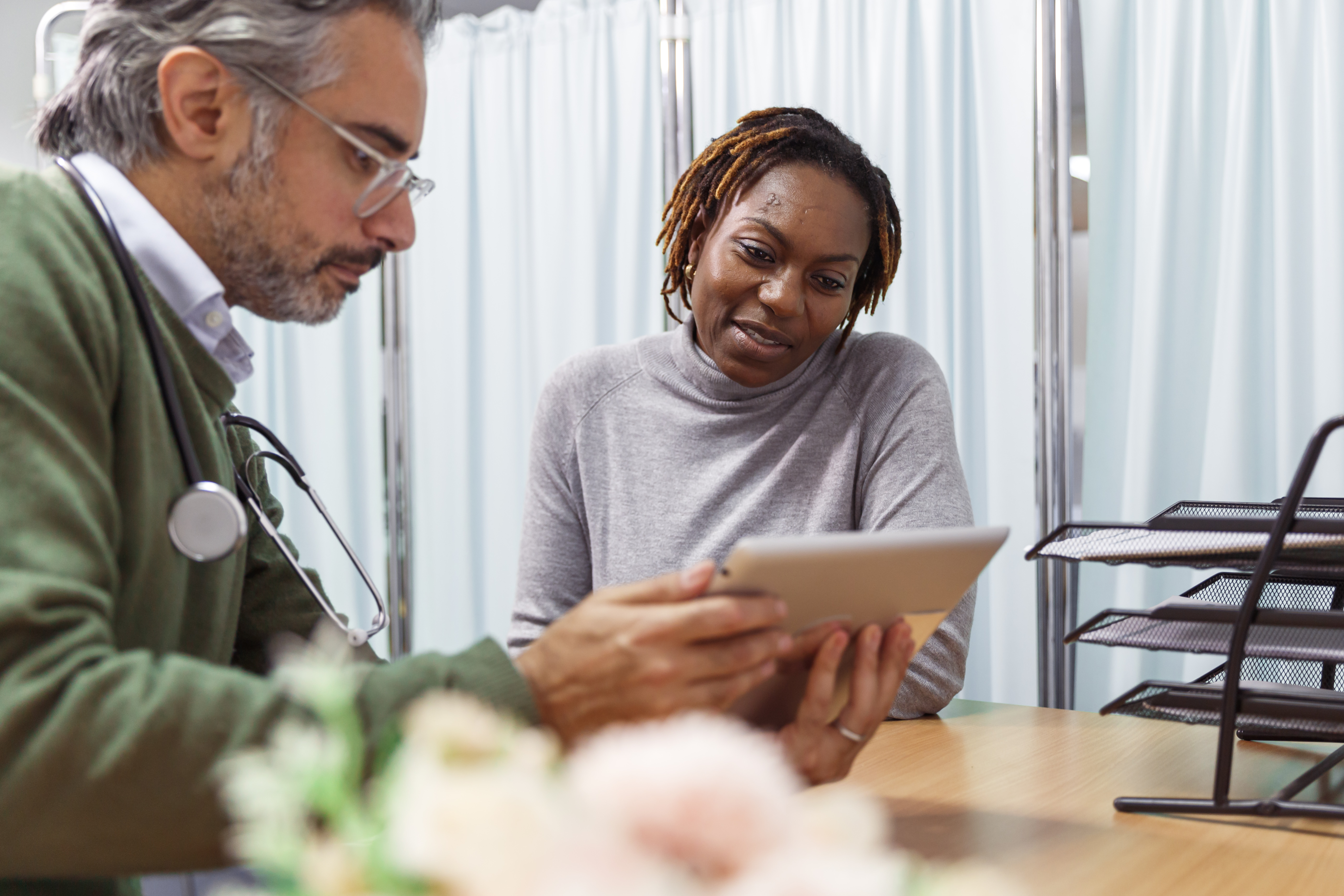 A male consultant and female patient looking at a tablet screen.